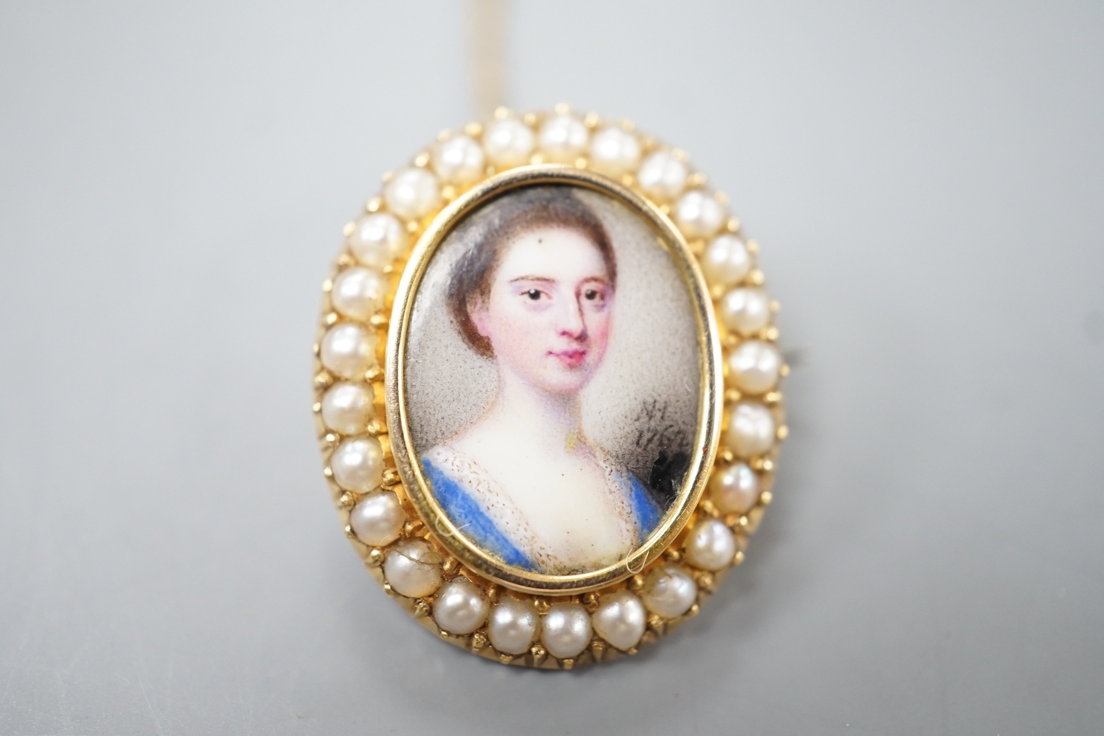 Attributed to Nathaniel Hone (1718-1784) a portrait miniature brooch, the 18th century inset enamel on copper portrait of a young lady mounted and backed in yellow metal, bordered in seed pearls, initialled and dated NH,